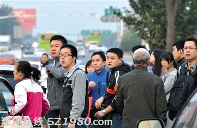 沒擠上的乘客翹首企盼下一輛公交車的到來。