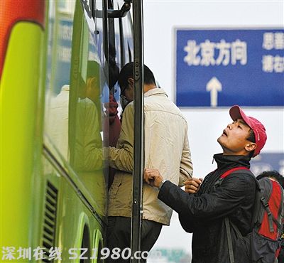 一名乘客在車門口往車?yán)飶埻?，看是否還有空位能擠進(jìn)去。