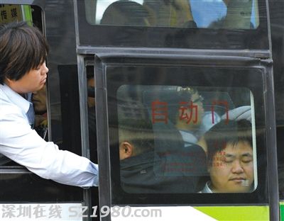 售票員用手將門口的乘客往里推，以便車門能順利關(guān)上。